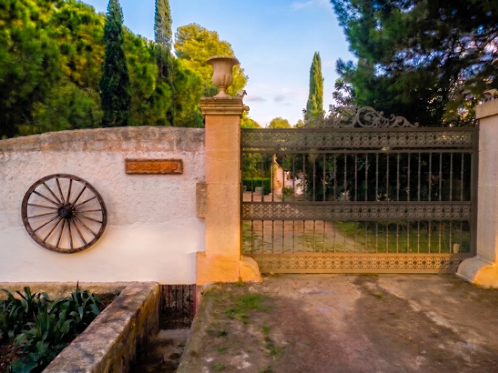 Monumentales Portal und schmiedeeisernes Eingangstor der Finca Cassou mit Namensschild und Bewässerungsgraben